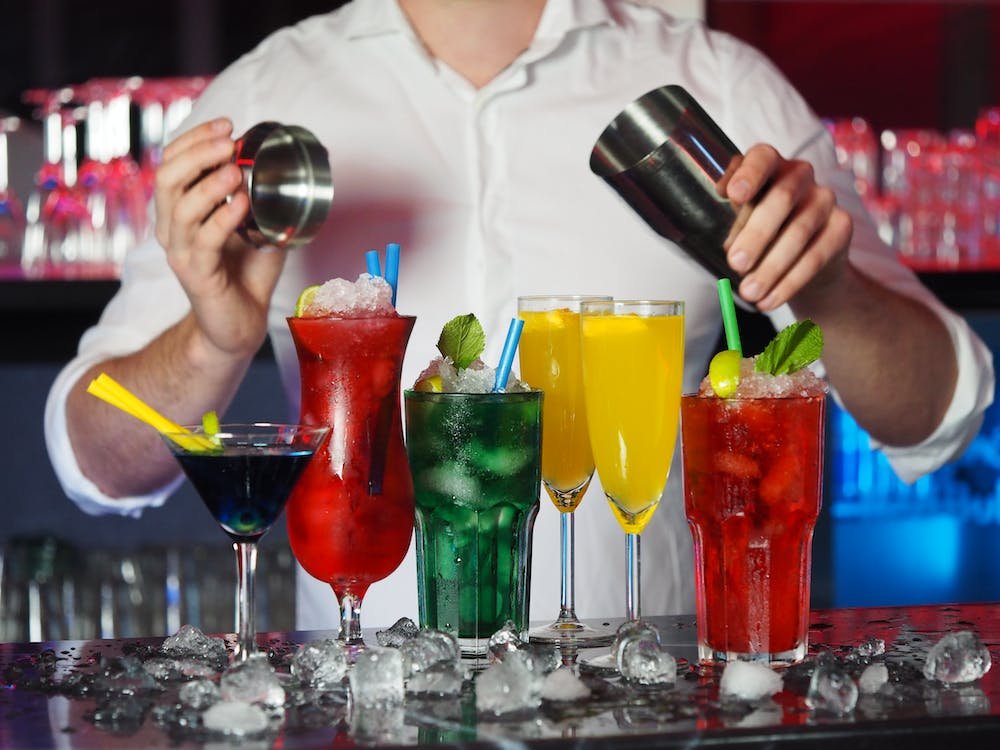 A bartender prepares an array of vibrant cocktails, including a sparkling apple cider drink, perfect for complementing a diverse brunch menu.