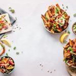 A delicious happy hour recipe spread featuring crispy fiesta fries loaded with fresh salsa, herbs, sour cream, and a tangy lemon garnish, ready to tantalize your taste buds.