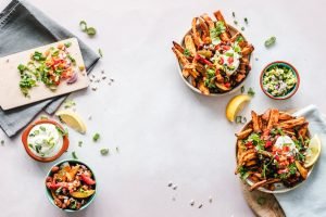 A delicious happy hour recipe spread featuring crispy fiesta fries loaded with fresh salsa, herbs, sour cream, and a tangy lemon garnish, ready to tantalize your taste buds.