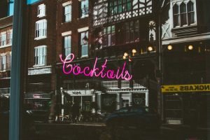 A neon sign spelling 'Cocktails' illuminates the front of a trendy downtown bar, inviting patrons to explore its menu of inventive drinks.