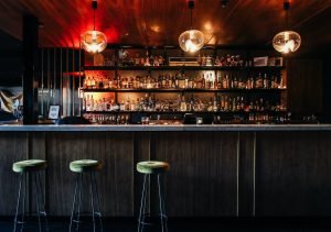Elegant bar setting in Yaletown, Vancouver, showcasing an array of spirits under warm lighting, with plush bar stools inviting an intimate dining experience.